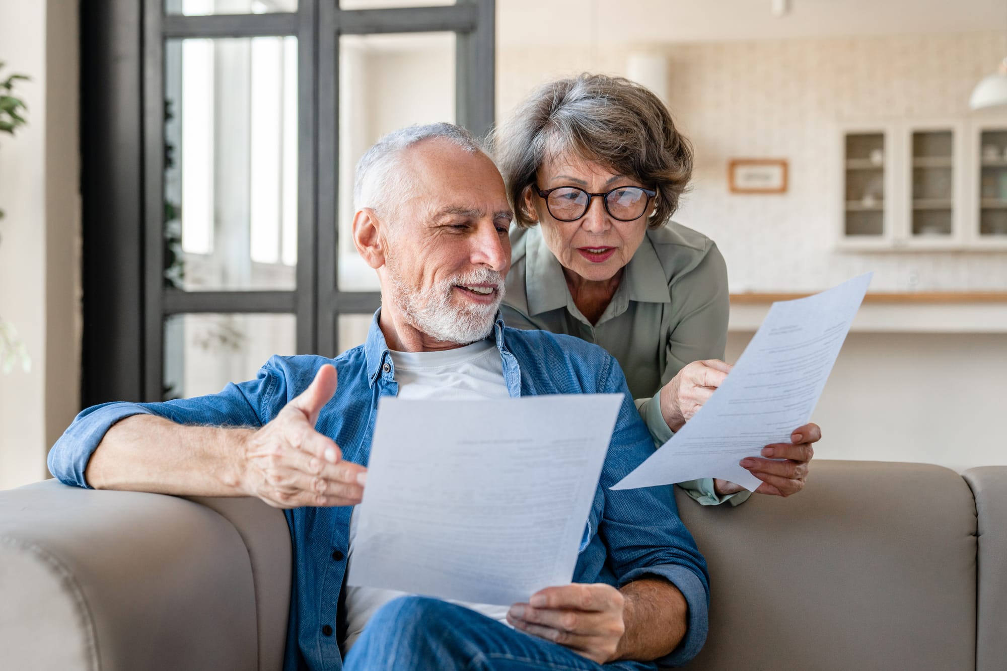 A couple reading through documents together on the couch